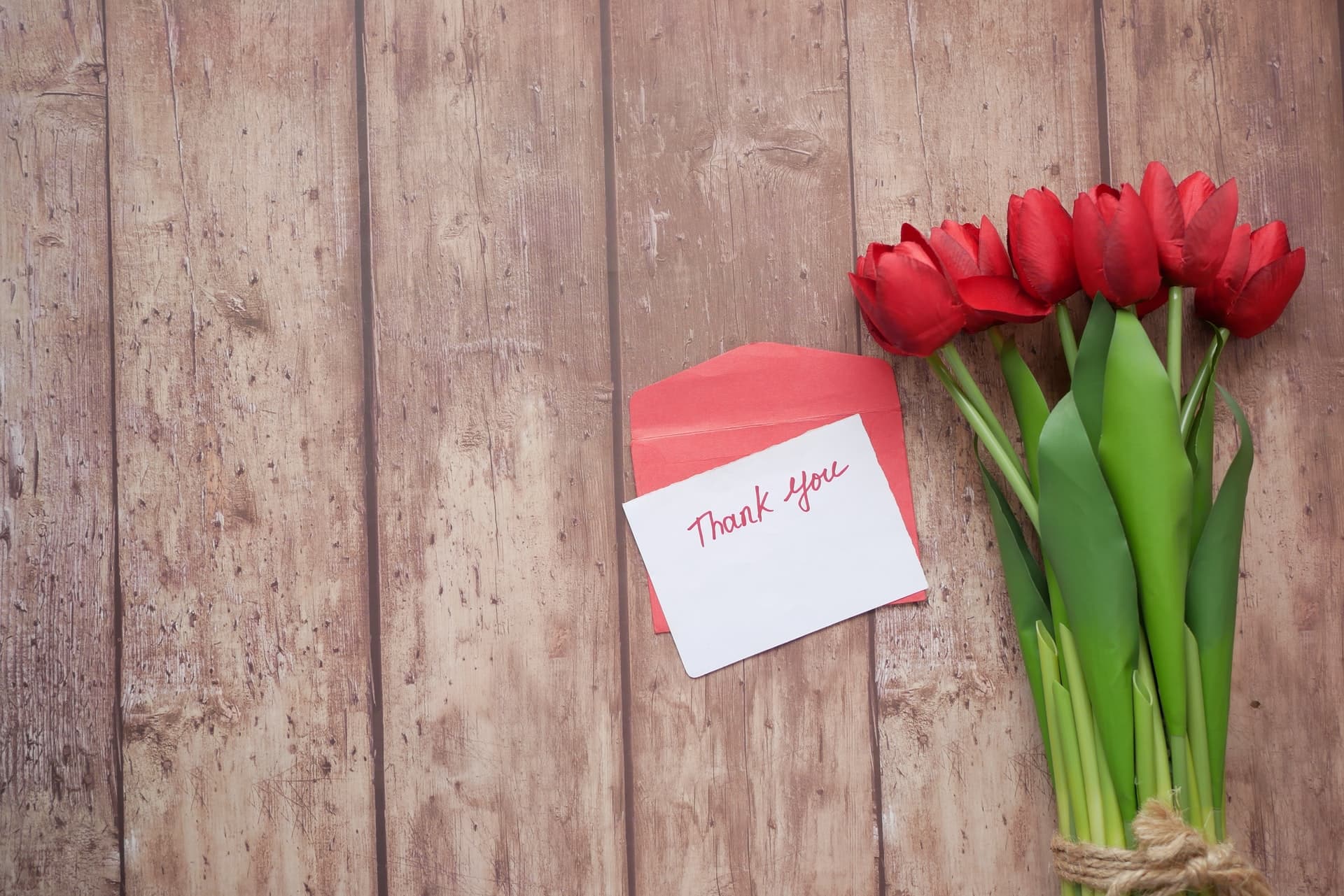 thank you message, envelope and red tulip flower on wooden background.